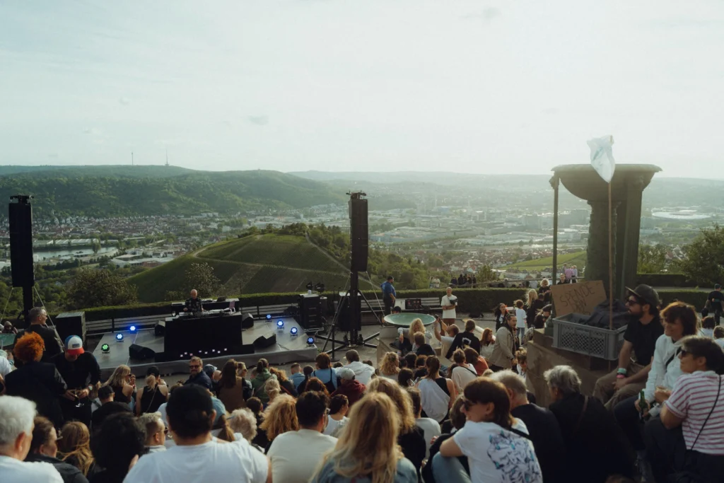 Ein Publikum sitzt bei einer Open-Air-Spendenveranstaltung auf der Anhöhe bei der Grabkapelle mit Blick über Stuttgart.