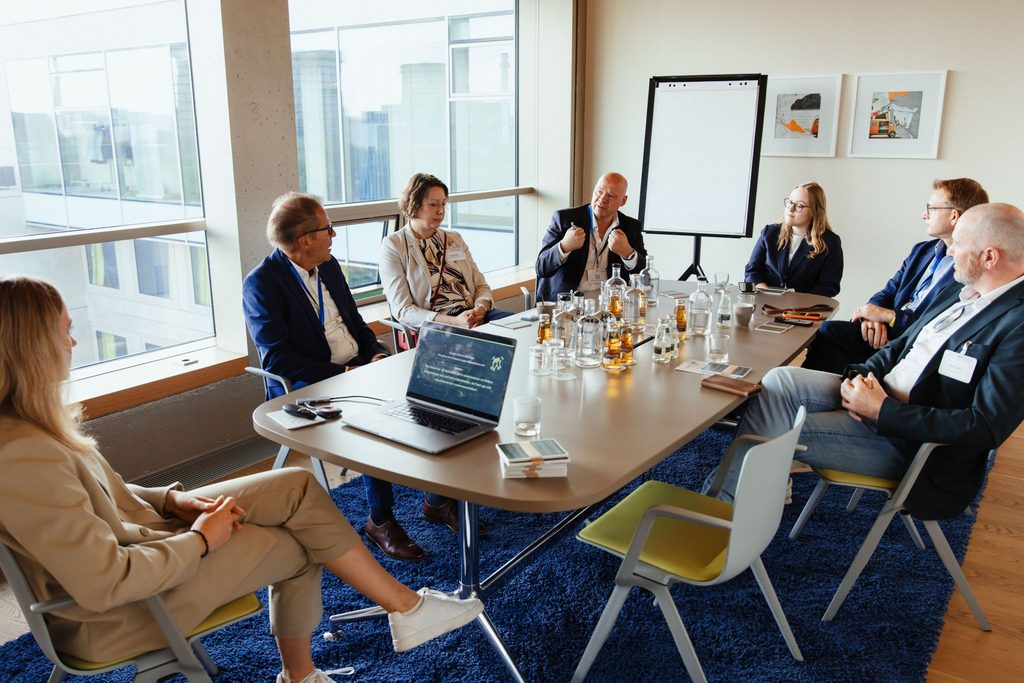 Elisa Heinzelmann sitzt bei ihrer Masterclass zu "Generation Z verstehen und erfolgreich zusammenarbeiten" mit sechs Unternehmer und Unternehmerinnen am Tisch und führt eine offene Diskussion. 