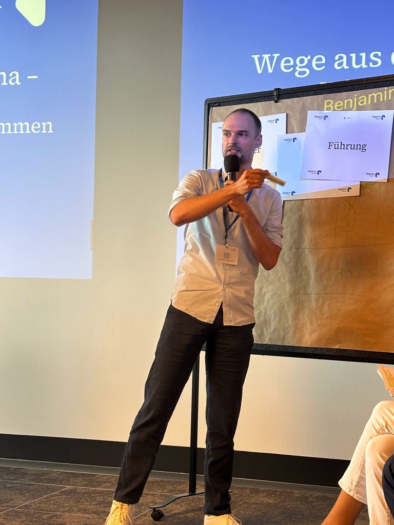 Benjamin zeigt im Rahmen seines Impulsdialogs auf eine Metawand, an der er gerade etwas demonstriert.