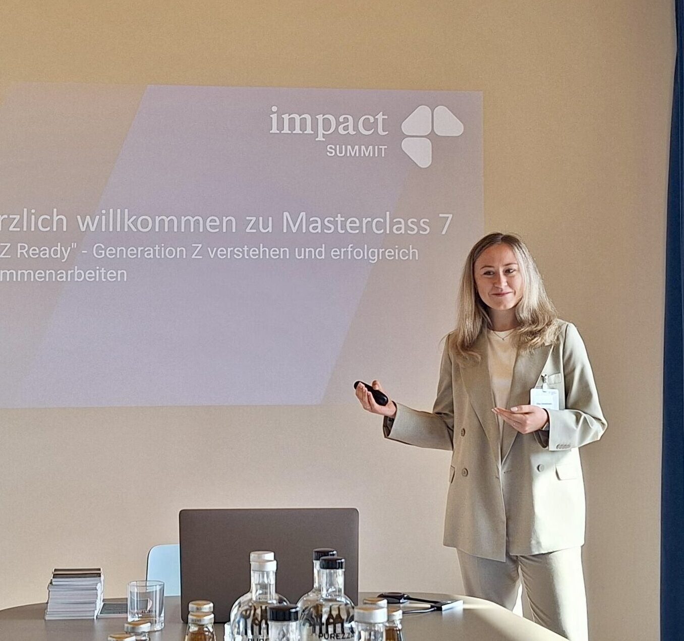 Elisa hält ihre Masterclass. Im Hintergrund ist die erste Folie ihres Impulsvortrages mit dem Vortragstitel "Willkommen zu Masterclass 7 - Generation Z verstehen und erfolgreich zusammenarbeiten" zu sehen. 